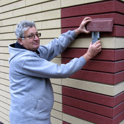 Семен Кернер демонстрирует плитку из декоративного камня и фрагмент стальной конструкции для утепления стен.